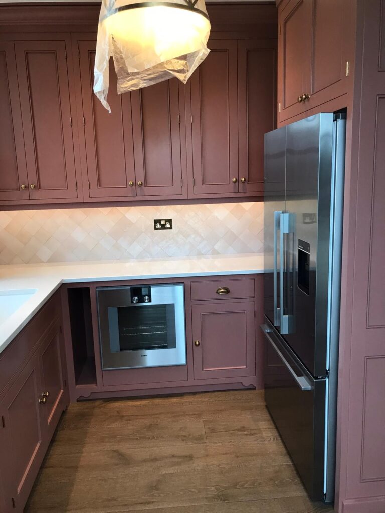 Kitchen with painted cabinetry, built-in oven, tall fridge freezer and a tiled splashback above the worktop