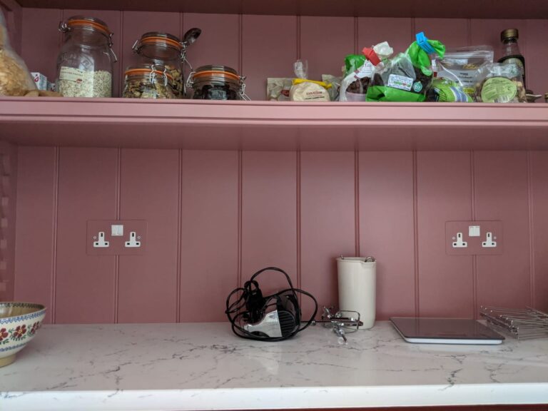 Pantry shelving with storage jars above a worktop, holding kitchen gadgets and baking ingredients in jars and packets