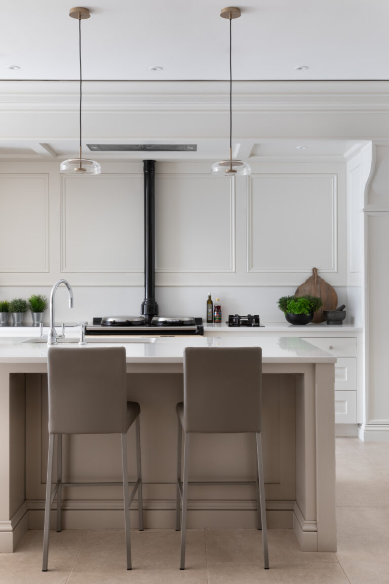 Kitchen island with two bar stools facing an Aga range, pendant lights hanging above the counter