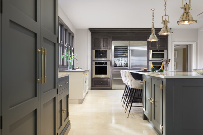 Kitchen with Down Pipe cabinetry, brass handles, integrated fridge-freezer and ovens, and a Caesarstone island with bar stools