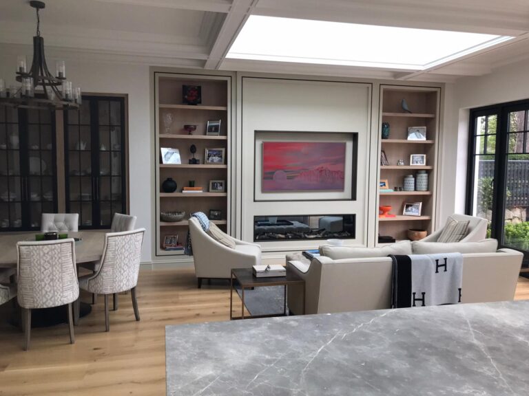 Living room with built-in shelving either side of a central fireplace, dining table and sofas arranged nearby