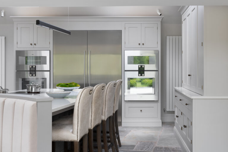 Kitchen island with upholstered banquette seating, integrated fridge freezer and twin ovens built into painted cabinetry
