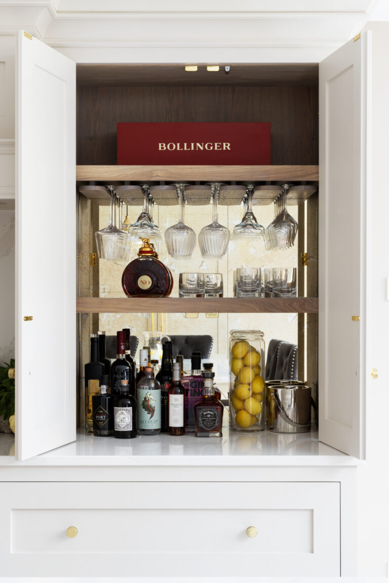Open Shaker-style twin doors reveal a stained oak interior with glass racks, spirits and mirrored shelving