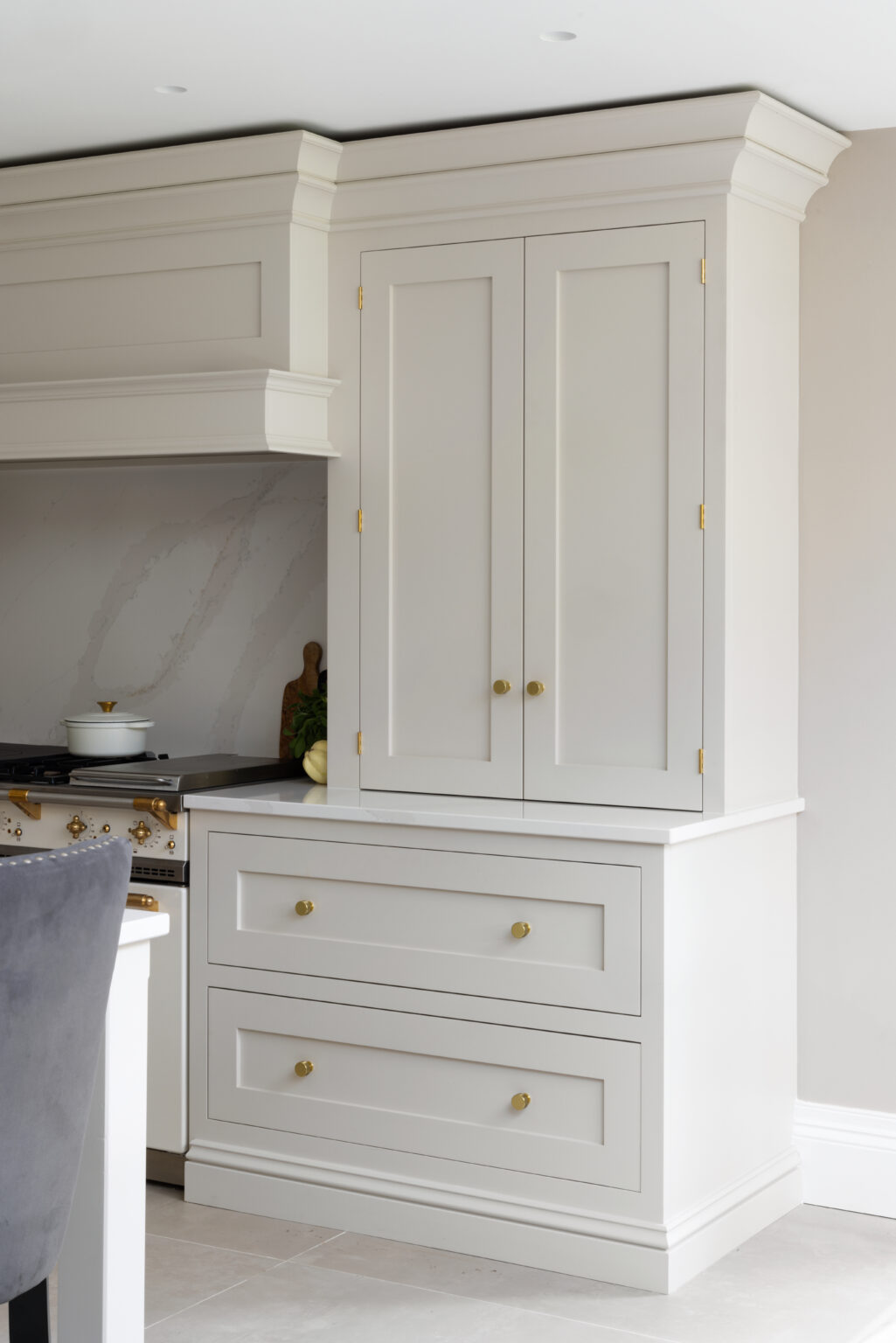 Shaker-style twin cabinet doors and drawers with brass knobs, built into the kitchen cabinetry beside the range