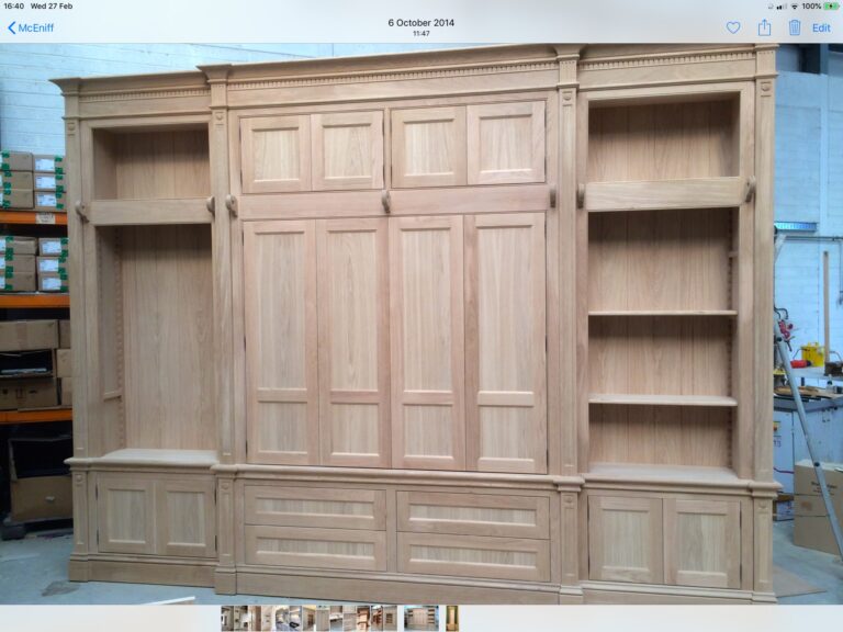 Large bespoke fitted unit in a workshop, with panelled cupboard doors, open shelving and drawers below