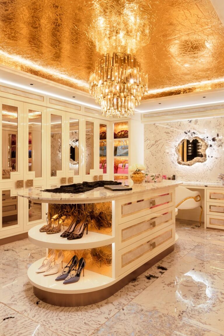Dressing room with gold leaf ceiling, mirrored wardrobes and a central island displaying shoes and accessories
