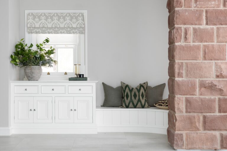 White cabinetry and a cushioned bench seat sit beside the exposed sandstone wall in the reading nook