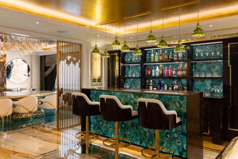 Green agate bar with gold-finished stools, pendant lights and a backlit shelved drinks display