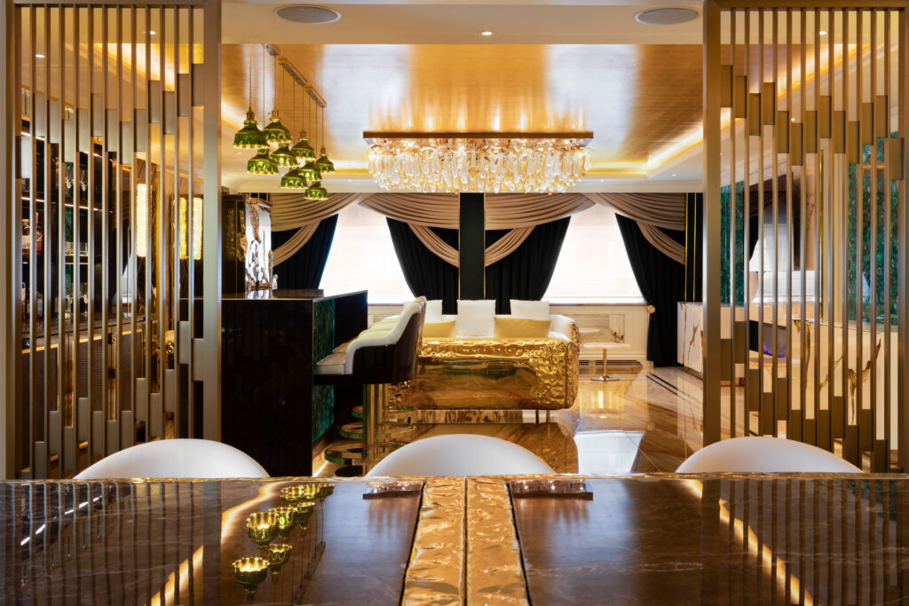 Dining table with gold detailing leads to a green agate bar with gold fittings and crystal chandelier