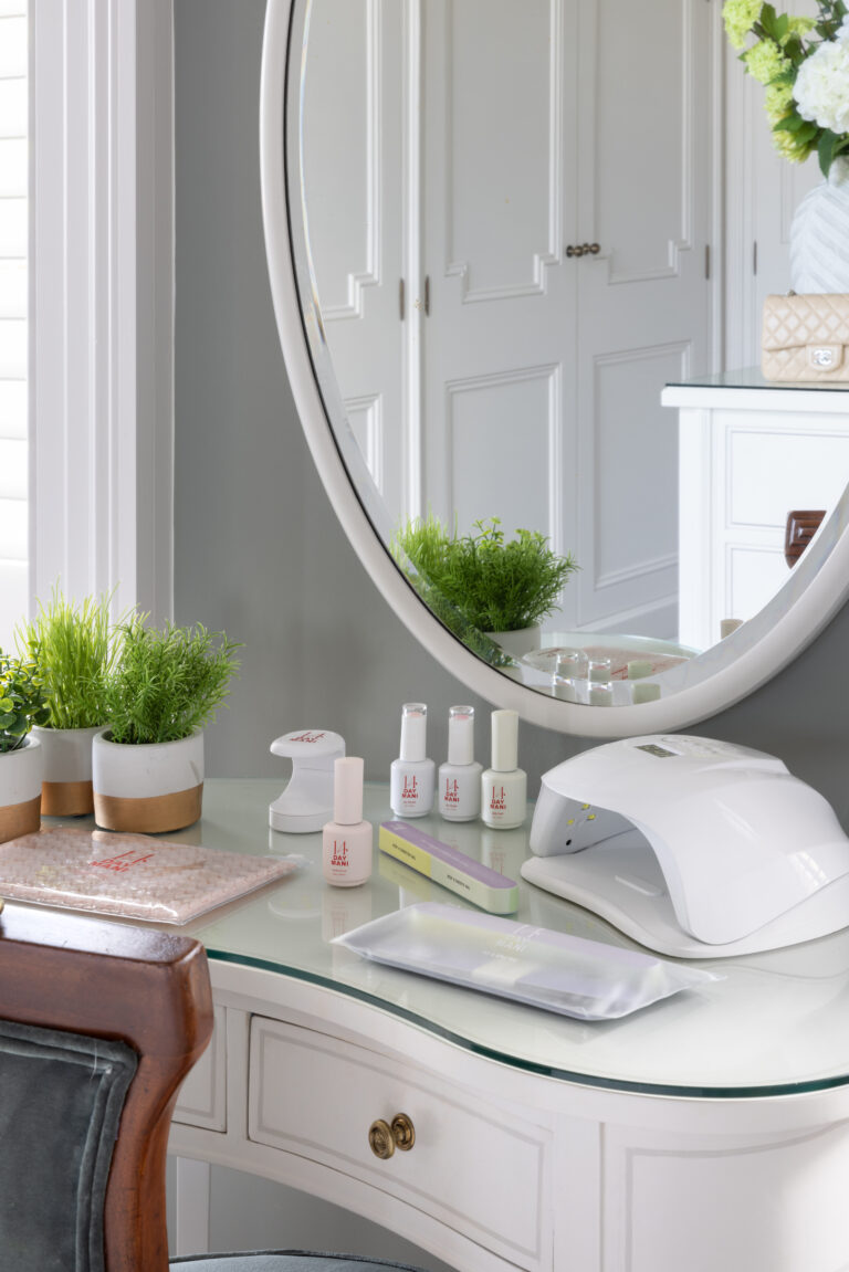 Dressing table with round mirror, glass top and brass handles, set against panelled fitted wardrobes