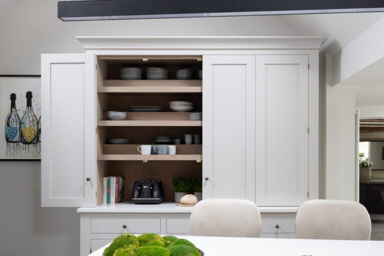 Open dresser cupboard with shelved crockery, cookbooks and a toaster, set above a vaulted ceiling kitchen diner