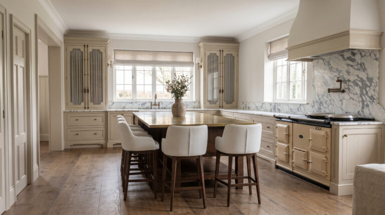 Kitchen with a central island, upholstered bar stools, stone splashback and a cream range cooker