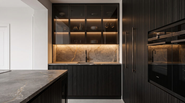 Kitchen with dark ribbed cabinetry, veined stone splashback, illuminated glass-fronted units and a built-in Siemens oven