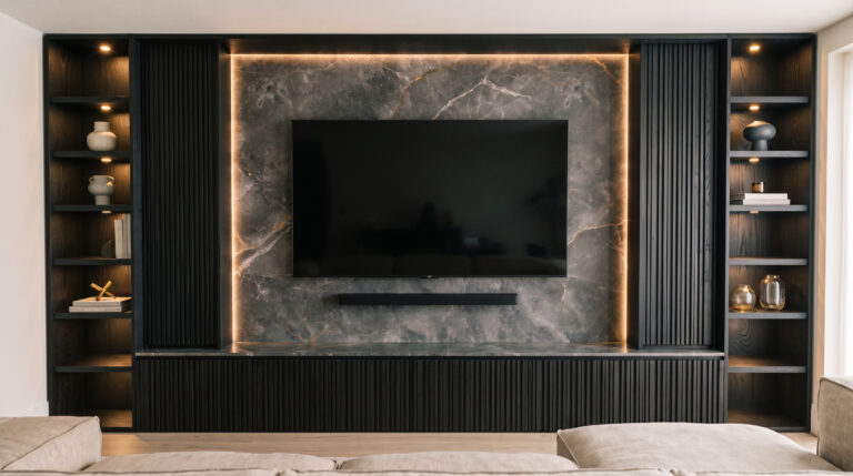 Living room media wall with fluted dark cabinetry, open display shelving, backlit stone panel and wall-mounted television