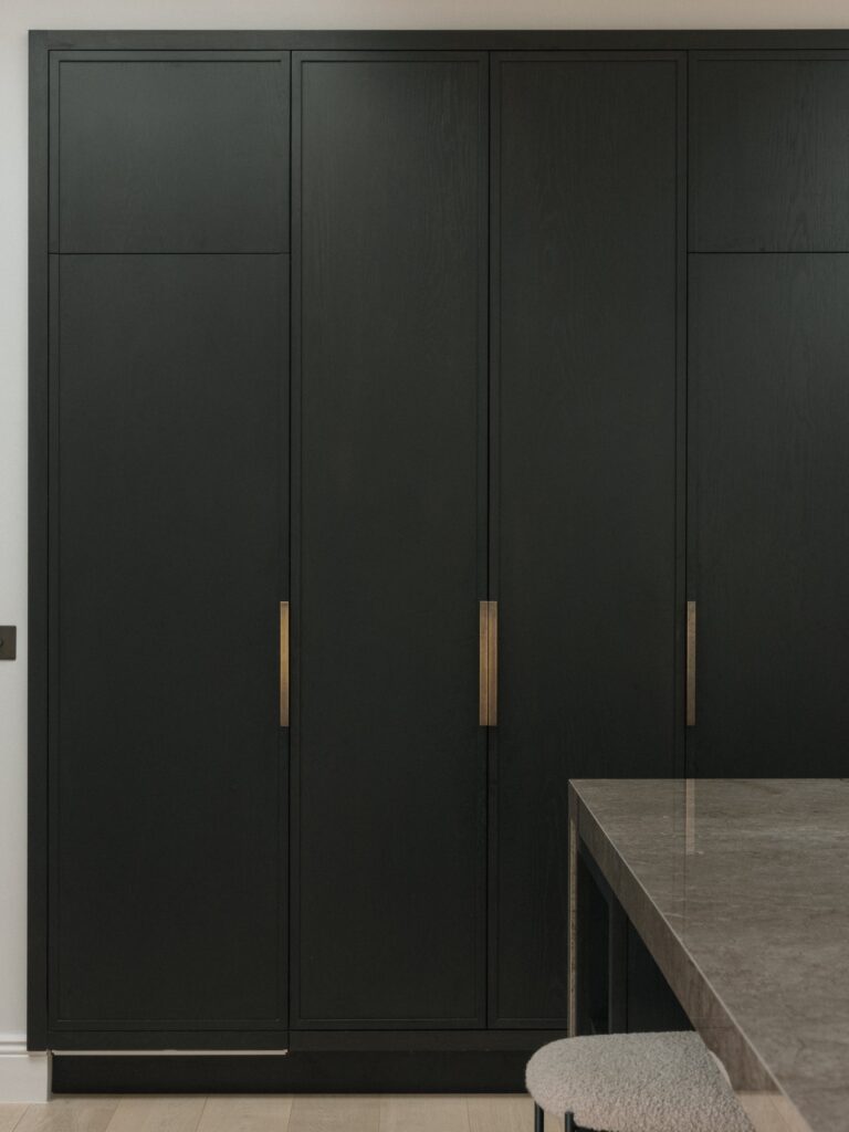 Tall black-stained oak doors with long aged brass bar handles