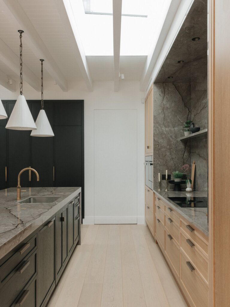 Rooflights and white-painted beams over a black-stained oak island with a brass tap, Cotton White oak run opposite