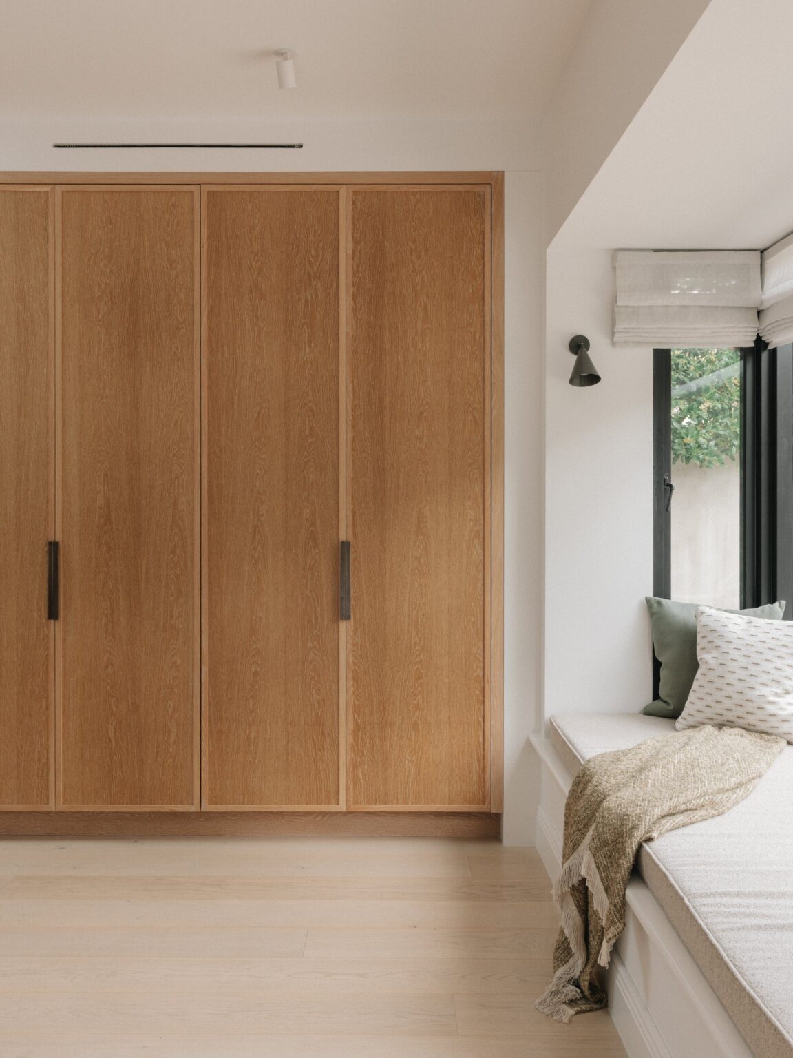 Pair of tall Cotton White oak pocket doors beside a window seat